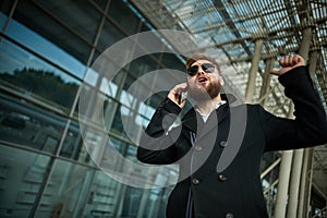 Urban business man in sunglasses talking smart phone traveling walking outside