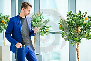 Urban man with cellphone in airport. Casual young boy wearing suit jacket. Caucasian man with cellphone at the airport