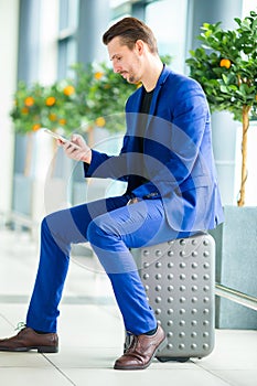 Young man with cellphone in international airport waiting for boarding