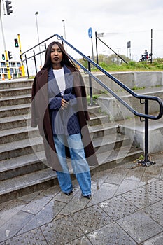 Urban Chic: Young Black Woman in Fashionable Layered Outfit on City Steps