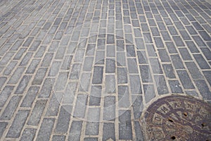 Urban city street brick rock road with cast iron manhole cover