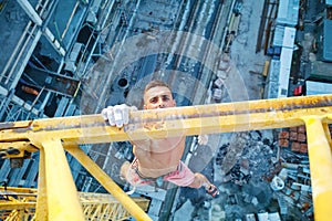 Urban climbing: rock climber hanging on jib of construction crane with one hand