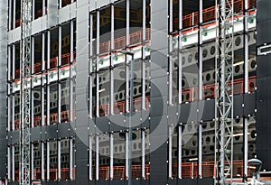 Urban construction site with cladding being fastened to the metal framework of a large commercial development with orange fence photo