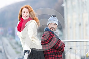 Urban couple on the bridge. Happy couple standing back to back. Man and woman look in one way. Smiling red hair lady and happy man