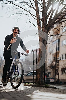 Urban cyclist with headphones using smart phone on sunny city street