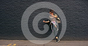 Urban dancer woman, city and brick wall with movement, confident energy and freedom with streetwear. Hip hop girl, free