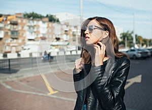 Urban fashionable girl posing in a leather jacket outdoors in the city