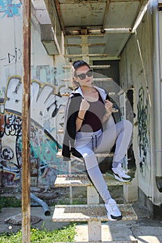 Urban girl sitting on rusted stairs with glasses