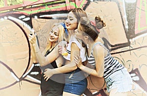 Urban girls have fun with retro vintage photo camera outdoor near grunge wall, image toned.