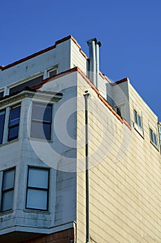 Urban house or home exterior with white or beige stucco facade on building with flat roof and visible chimney vents and
