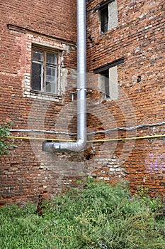 Urban landscape with the wall of an old house with windows and a ventilation pipe