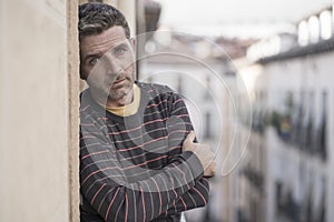 Urban lifestyle emotional portrait of 40s handsome man sad and depressed at home balcony leaning upset feeling worried suffering