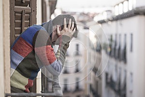 Urban lifestyle emotional portrait of young attractive and depressed man at home balcony leaning upset feeling desperate suffering