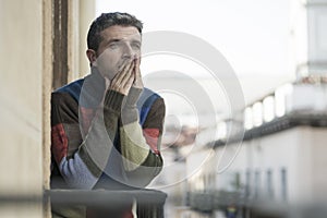 Urban lifestyle emotional portrait of young attractive and depressed man at home balcony leaning upset feeling desperate suffering