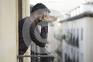 Urban lifestyle emotional portrait of young attractive and depressed man at home balcony leaning upset feeling desperate suffering