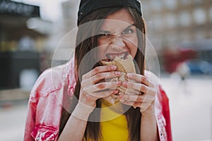 Pretty hipster girl hungrily eating hot dog photo