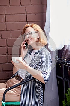 Urban living - woman smiling speaking by her phone during a coffee break savoring a moment of her busy day.