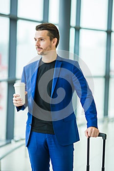 Urban man with coffee inside in airport. Casual young boy wearing suit jacket. Caucasian man with cellphone at the