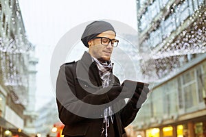 Urban man holdin tablet computer on street