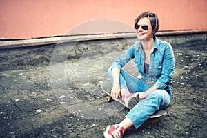 Urban and modern lifestyle, hipster smiling girl with skateboard wearing jeans, sunglasses