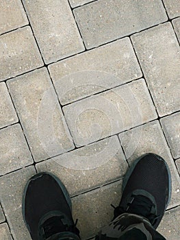 Urban pavers are arranged symmetrically and the man`s feet