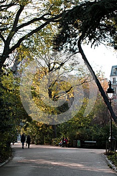 Pedestrians walking on city pathway in park in sunny fall