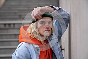 Urban portrait of handsome trendy hipster guy with long hairstyle posing outdoors