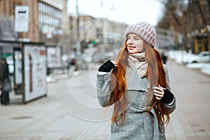 Urban portrait of splendid redhead girl with long hair wearing w