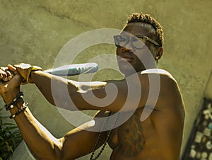 Urban portrait of young aggressive and upset violent black afro American man using baseball bat threatening at grunge corner in