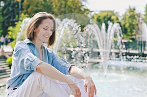 Urban portrait of young elegant business woman in eye glasses and casual clothes in city. Woman walking in green park, relaxing