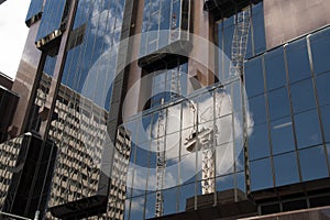 Reflection of crane from worksite in exterior of glass office building