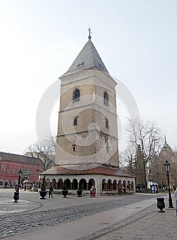 Urban scene with people walking near old stone tower