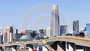 Urban skyline in downtown San Francisco on a sunny day, with clear blue sky; vehicles driving on a raised freeway in the