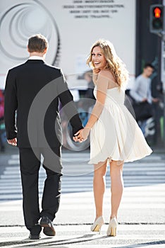 Urban sophistication. A beautiful woman glances back and smiles as she crosses the street with her boyfriend.
