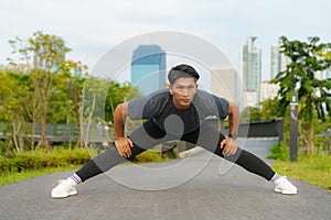 Urban sports - Asian young man is doing warming up before running in the city on a beautiful summer day