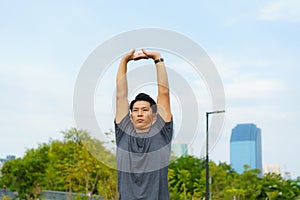 Urban sports - Asian young man is doing warming up before running in the city on a beautiful summer day