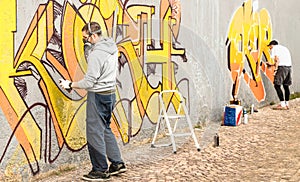 Urban street artists painting colorful graffiti on generic wall