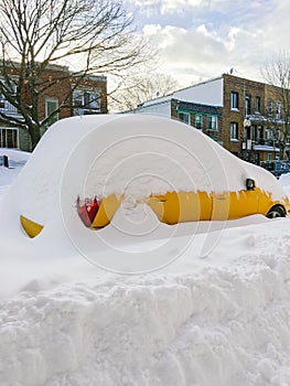 Urban street with a yellow car stuck in snow