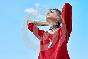 Urban Style. Young stylish woman standing outdoors holding head breathing freedom joyful bottom view