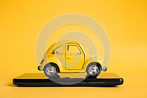 Urban taxi mobile online application concept. Toy yellow taxi car model. Hand holding smart phone with taxi service app