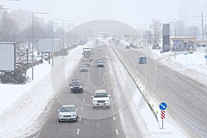 Urban traffic in winter. Cars driving on a snowy road, a blizzard, poor visibility