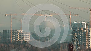 Urbanization - urban growth, tower cranes, steam from power plant smokestack