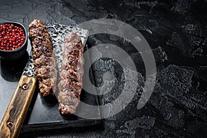Urfa kebab, ground beef and lamb meat grilled on skewers. Black background. Top view. Copy space