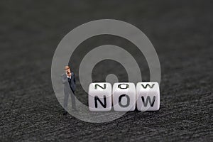 Urgency, stop postpone and procrastination, motivation concept, miniature figure businessman standing with white cube with