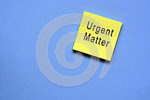 Urgent matter text on yellow sticky note with blue background