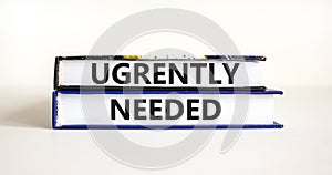 Urgently needed symbol. Concept words Urgently needed on books on a beautiful white table white background. Business and urgently