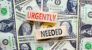 Urgently needed symbol. Concept words Urgently needed on wooden blocks on a beautiful background from dollar bills. Business and