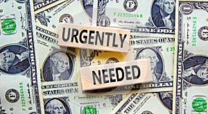 Urgently needed symbol. Concept words Urgently needed on wooden blocks on a beautiful background from dollar bills. Business and