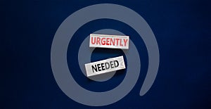 Urgently needed symbol. Concept words Urgently needed on wooden blocks on a beautiful black table black background. Business and