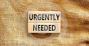 Urgently needed symbol. Concept words Urgently needed on wooden blocks on a beautiful canvas table canvas background. Businessman